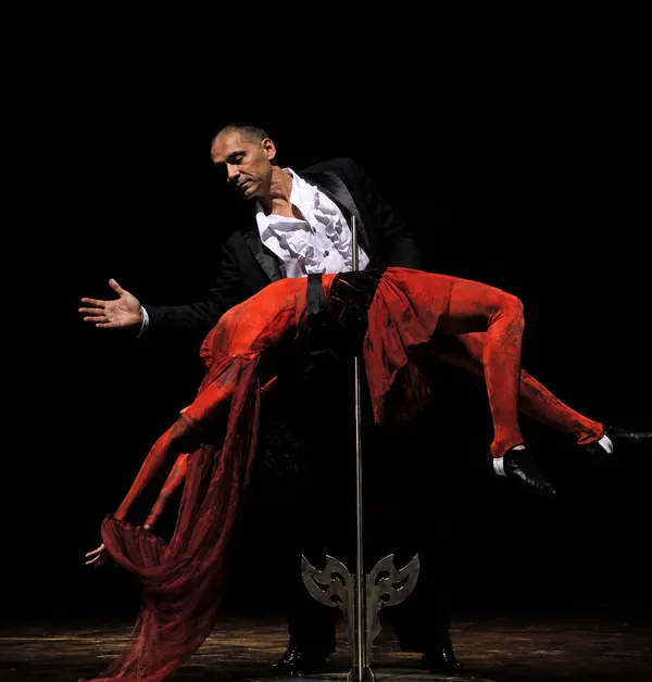 El mago suspende en el aire a una artista vestida de rojo