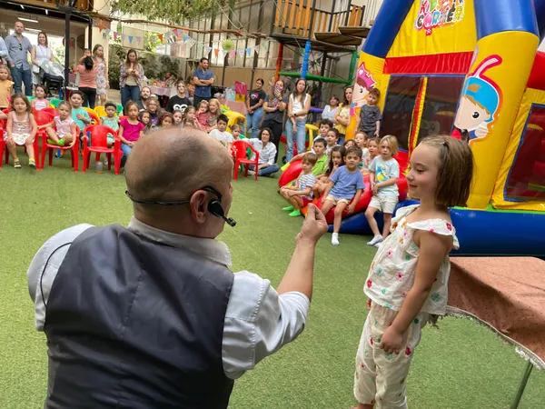 El mago muestra una moneda a la festejada frente a todos los invitados